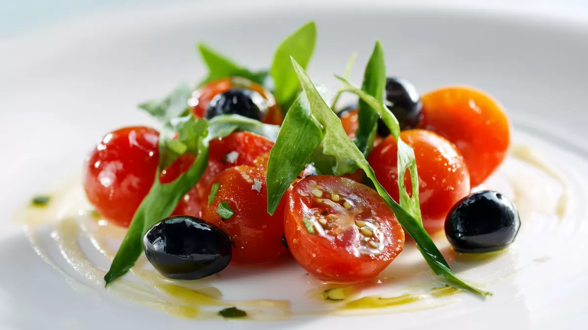 Tomaten Bärlauch Salat mit Oliven auf weißem Teller