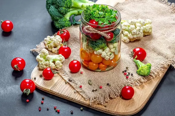 Tomaten-Kohl-Brokkoli und Gewürze in einem Glas auf einem Schneidebrett mit Leinen