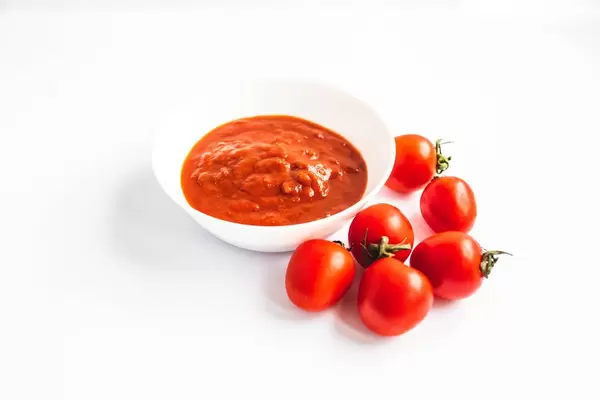 Tomatensoße auf einem Teller mit Tomaten auf weißem Hintergrund