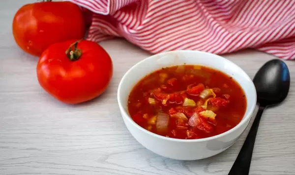 Tomato Soup in a White Bowl with tomatoes on a Side