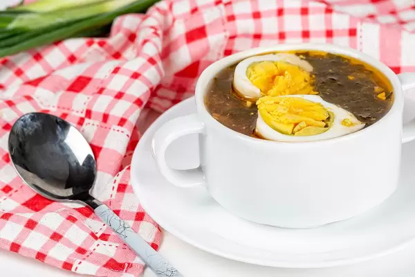 Tomato soup with herbs and chicken eggs in a white tureen