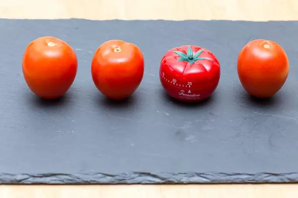 Tomatoes with a tomate shaped kitchen clock on a black stone