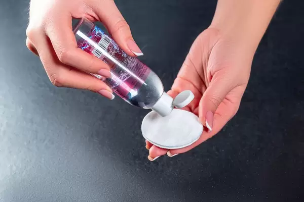 Tonic for the face with a cotton disc in the female hand