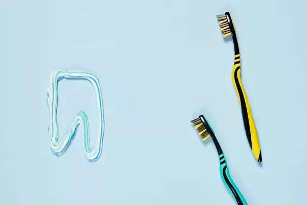 Tooth made of paste, and brushes on color background