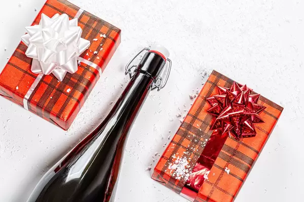 Top view a bottle of champagne and two gift boxes. The concept of Christmas