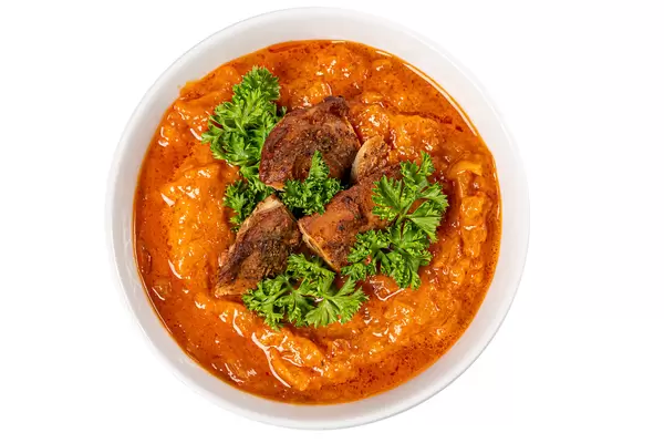 Top view, a bowl of carrot and squash soup with parsley and chicken