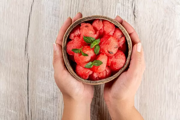 Top view, a bowl with fresh watermelon balls in women's hands