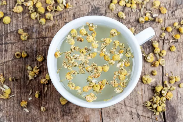 Top view, a cup of chamomile tea on an old wooden background