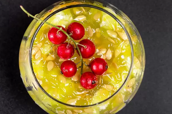Top view, a sprig of red currant on the pulp of a Kiwano fruit with seeds in a glass (Flip 2020)