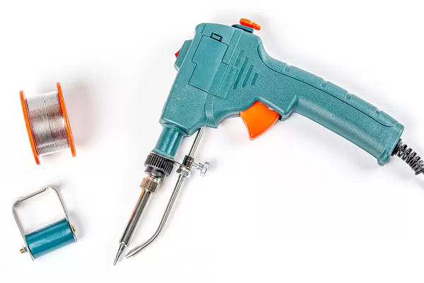 Top view, automatic tin soldering iron and tin coil on white