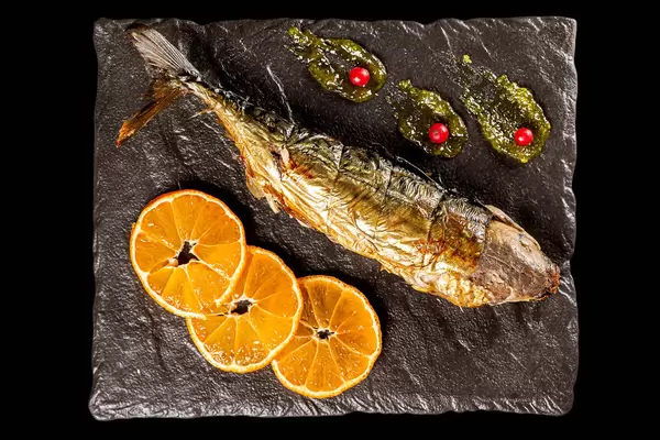 Top view, baked mackerel with orange slices and red currant berries