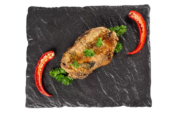 Top view, baked meat on a black stone tray