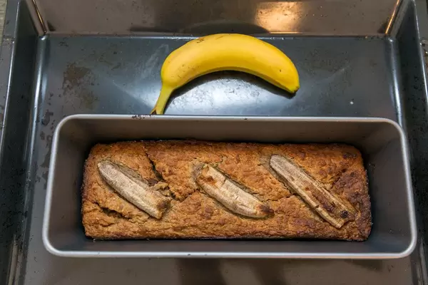 Top view Bananenkuchen in einer Backform und einer Banane auf dem Backblech