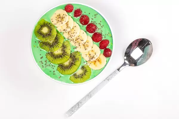 Top view, bowl of oatmeal with yogurt and fruits on white background