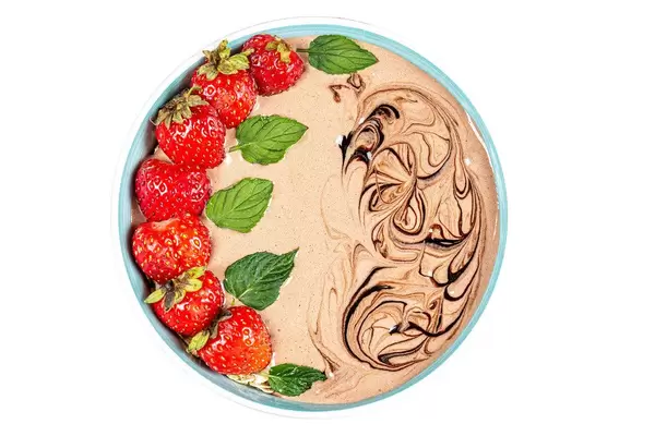 Top view, bowl of oatmeal with yogurt, strawberries and mint