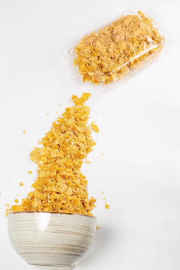 Top view, bowl with sprinkled cornflakes and cereals in a bag