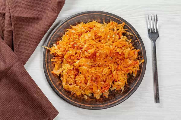 Top view braised cabbage on a plate on the table with a fork