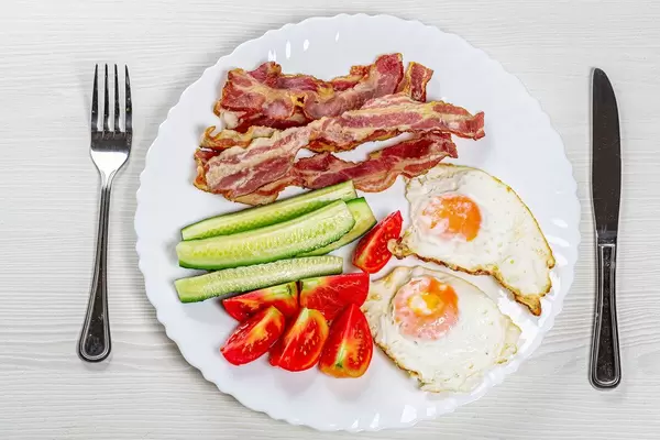 Top view Breakfast with scrambled eggs, bacon and vegetables