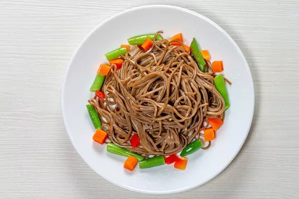 Top view buckwheat noodles with asparagus, carrots and sweet peppers on a white wooden background (Flip 2019)