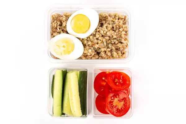 Top view, buckwheat with boiled eggs, cucumbers and tomatoes in plastic containers