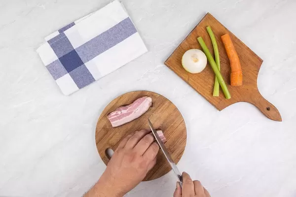 Top view Chef hands cutting Bacon on the wooden board