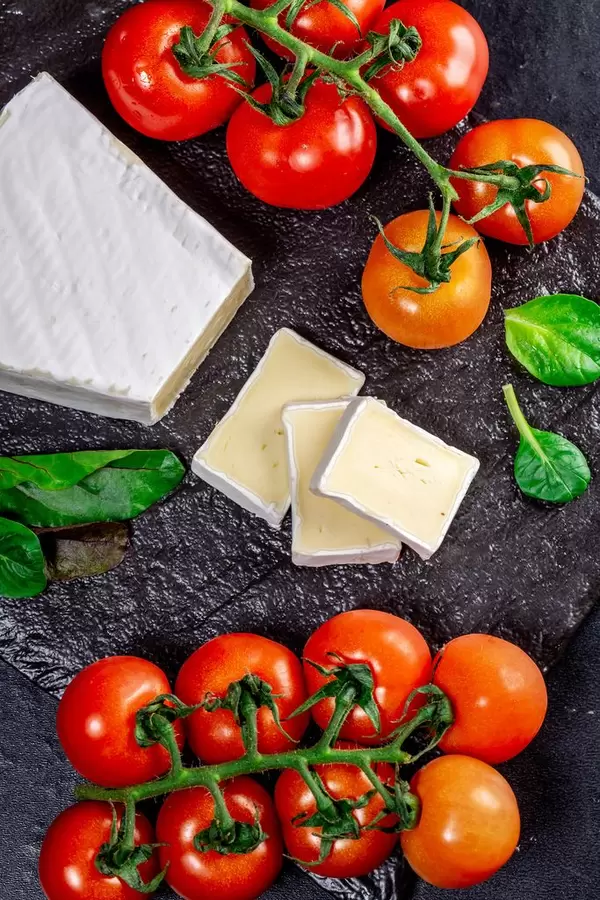 Top view cherry tomatoes and cheese with mold on black background (Flip 2019)