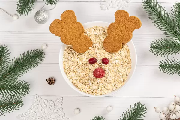 Top view, christmas breakfast in the form of a reindeer made of oatmeal and cookies