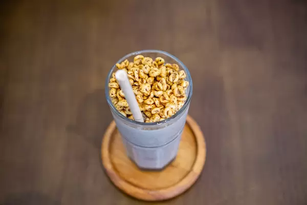 Top View Close Up Photo of Cookies and Cream Ice Blended Milkshake with Puffed Rice as Topping in a Cocktail Glass with Paper Straw