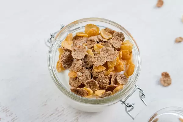 Top View Close Up Photo of Glass Container with Yogurt and Muesli on White Wooden Background