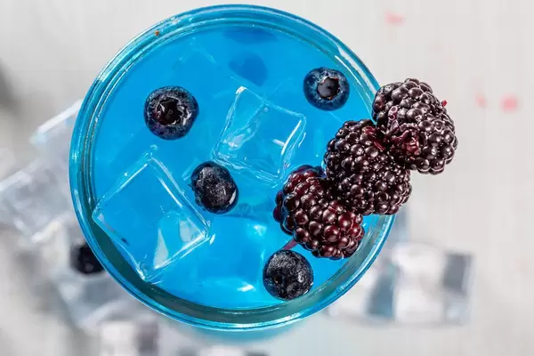 Top view, cocktail with ice cubes, mulberry and blueberry