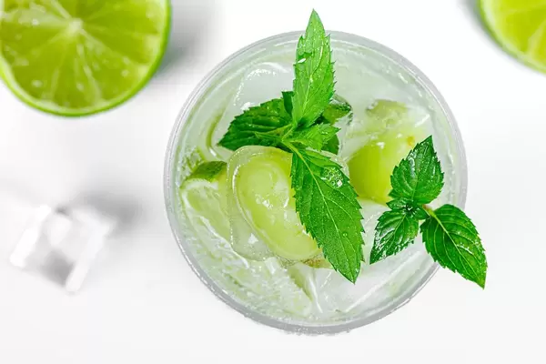 Top view, cold cocktail with ice, frozen lime, grapes and fresh mint