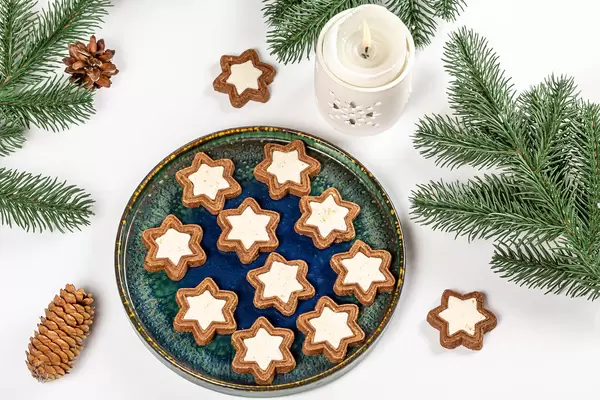 Top view, cookies in the shape of a star on a white background with branches of a christmas tree