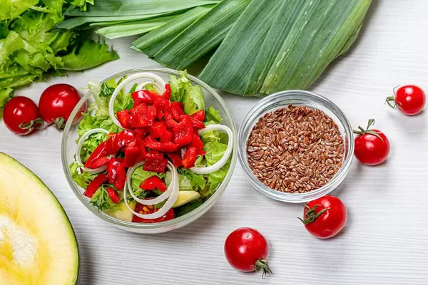 Top view dietary vegetable salad in glass bowl with ingredients on white wooden background (Flip 2019)