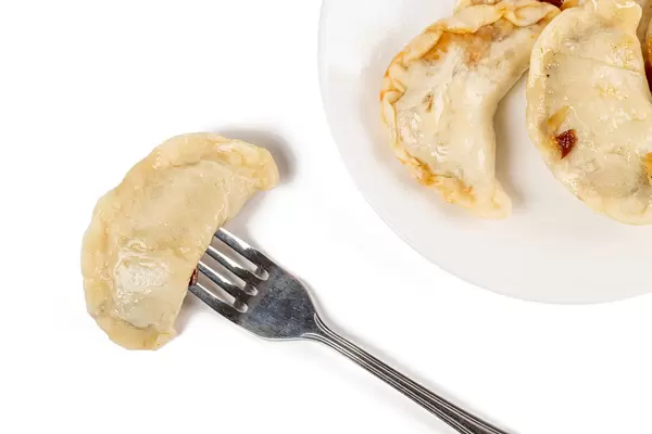 Top view, dumplings on a fork and in a plate, vareniki with cabbage