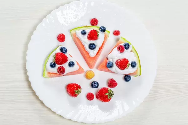 Top-view Erdbeeren, Himbeeren, Blaubeeren und weiße Sahne auf reifen Wassermelonen Scheiben