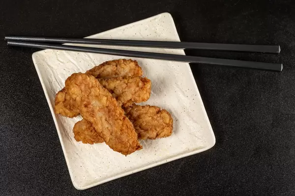 Top view, fish fillet cutlets with chopsticks on dark background