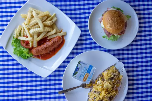 Top View Food Photo of Bread Roll with Ham and Cheese Filling, Muesli with Yogurt and Currywurst with French Fries for Breakfast and Lunch