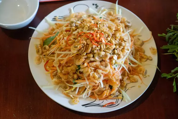 Top View Food Photo of Fresh Papaya Salad with Dried Shrimps, Herbs and Chili on a Wooden Table in a Restaurant in Can Tho, Vietnam