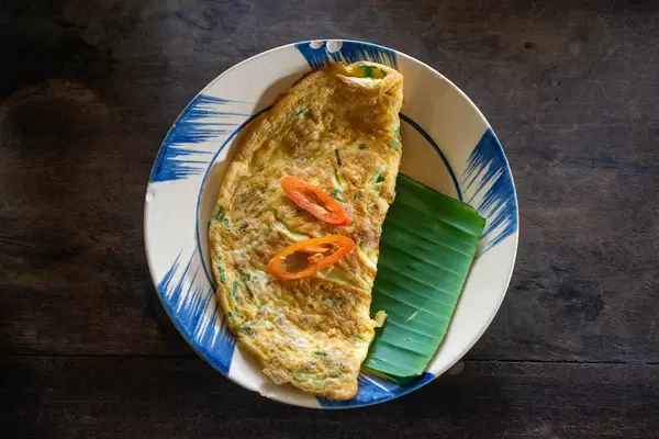 Top View Food Photo of Fried Egg Omelette with Minced Pork and Vegetables on a Banana Leaf in a Vietnamese Restaurant