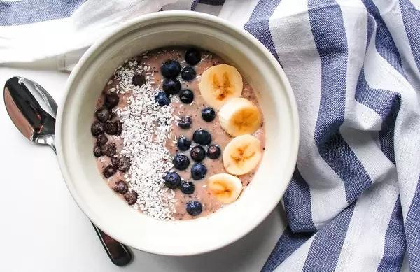 Top View Food Photo of Healthy Breakfast Smoothie Bowl with Banana, Blueberry and Coconut Rasp