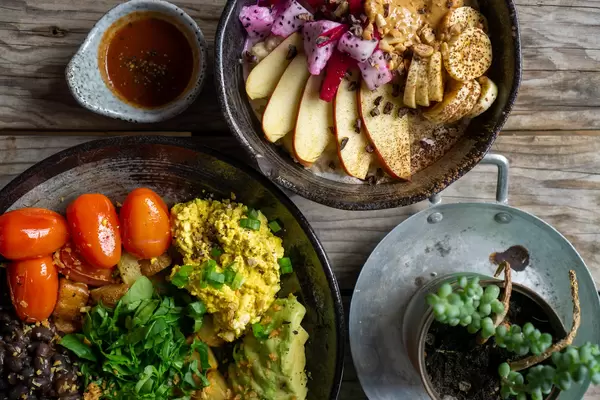Top View Food Photo of Healthy Vegan Meal with Scrambled Tofu, Cherry, Tomatoes, Avocado, Black Beans and Porridge with Fresh Fruits