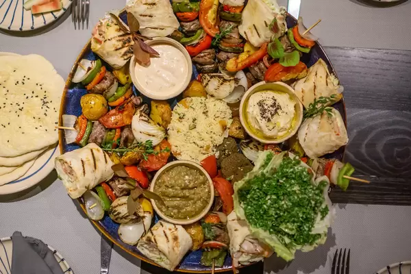 Top View Food Photo of Middle Eastern Sultan Platter with many different kinds of Foods such as Couscous, Hummus, Falafel, Beef Kebab, Chicken Shawama, Grilled Vegetables, Pita Bread and Sauces