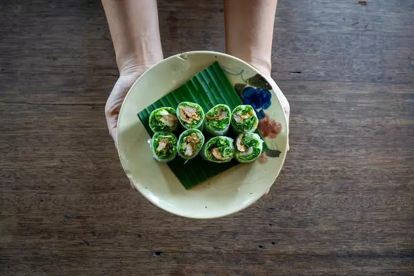 Top View Food Photo of Person holding a Plate of Vietnamese Summer Rolls with Grilled Meat and fresh Herbs
