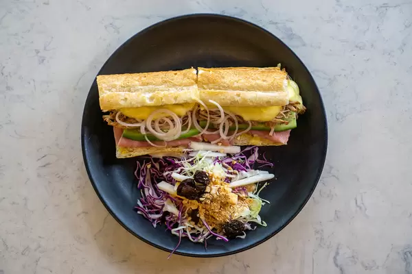 Top View Food Photo of Pulled Pork Sandwich with Pork, Swiss Cheese and Vegetables next to a Coleslaw Salad with Raisins and Peanuts