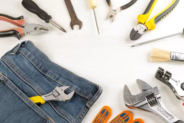 Top view, frame from work tools, glove and jeans on wooden background