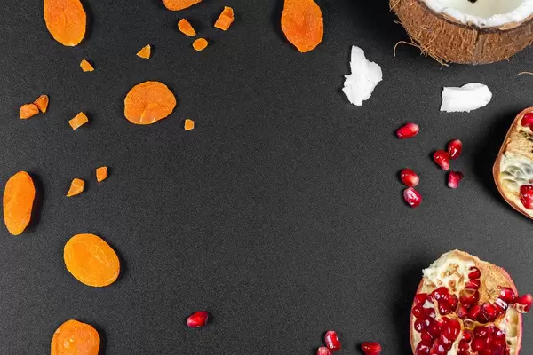 Top view, frame of dried apricots, pomegranate and coconut on a black background (Flip 2020)