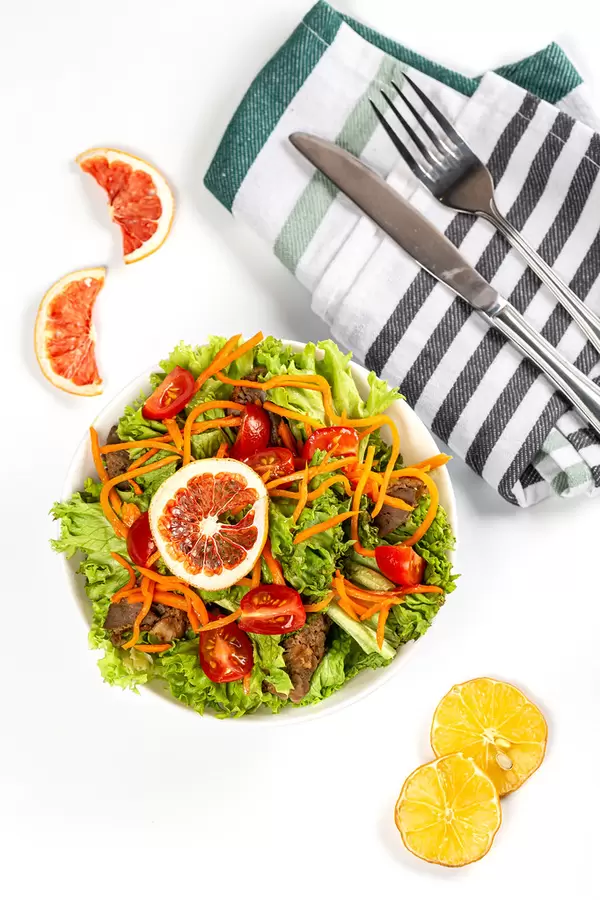 Top view, fresh salad with pickled carrots, lettuce, liver and tomatoes