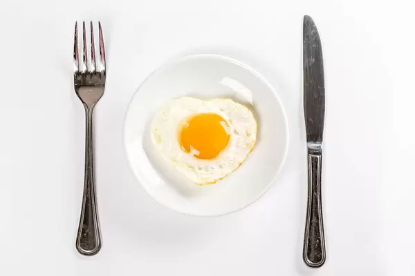 Top view, fried egg heart on a white plate