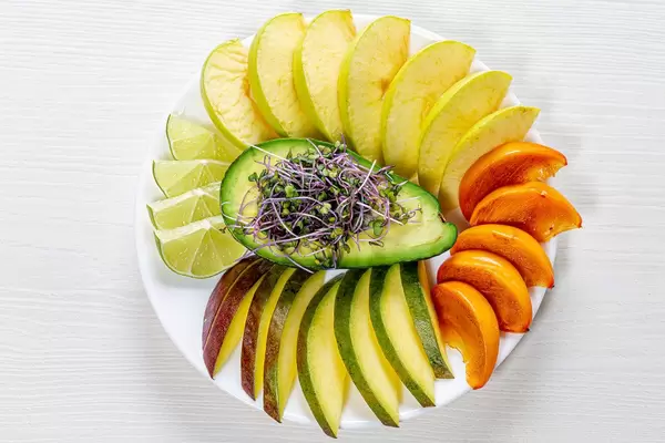 Top view fruit slicing on a white plate with avocado and micro green cabbage in the middle (Flip 2019)