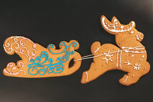 Top view, gingerbread deer and sleigh on black background